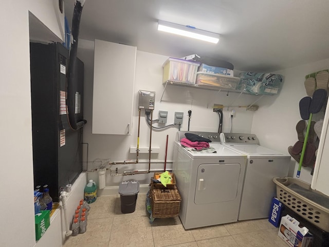 laundry room featuring heating unit, washer and clothes dryer, light tile patterned floors, and cabinets