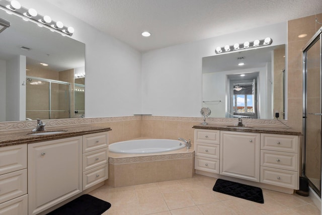 bathroom featuring tile patterned flooring, vanity, shower with separate bathtub, and a textured ceiling