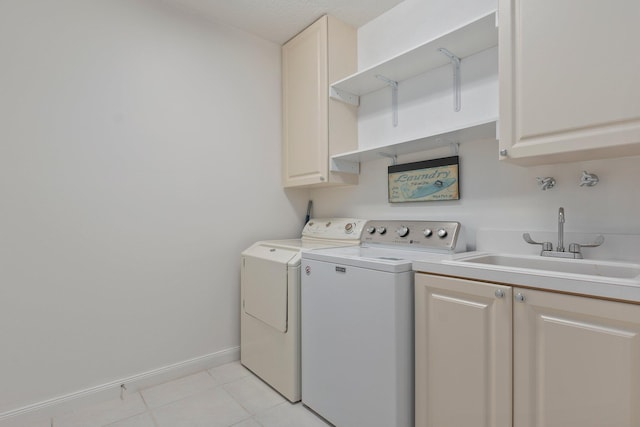 laundry area featuring separate washer and dryer, sink, light tile patterned floors, and cabinets