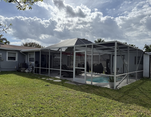 rear view of property with an outdoor pool, glass enclosure, cooling unit, a yard, and a patio area