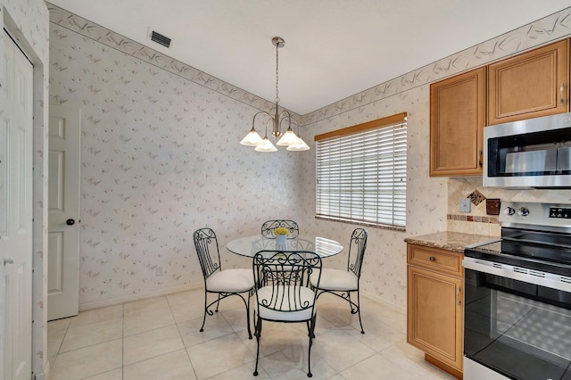 kitchen with light tile patterned flooring, appliances with stainless steel finishes, pendant lighting, a notable chandelier, and light stone counters