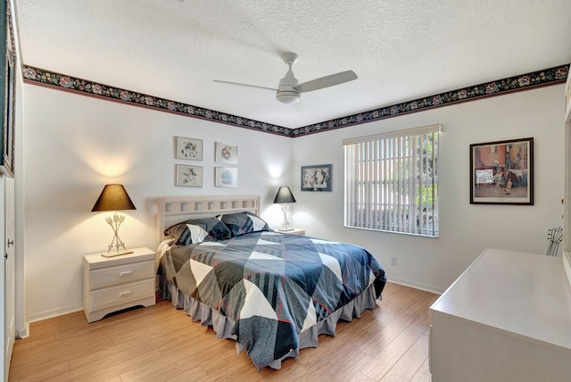 bedroom featuring ceiling fan, light hardwood / wood-style floors, and a textured ceiling