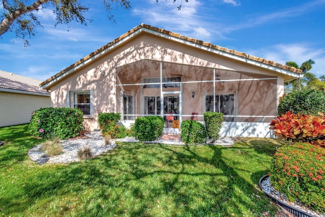 back of property with glass enclosure and a lawn