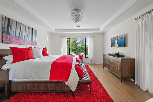 bedroom with a raised ceiling and light hardwood / wood-style floors