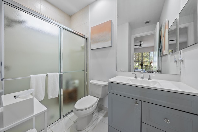 bathroom featuring a shower with door, ceiling fan, tile patterned flooring, vanity, and toilet