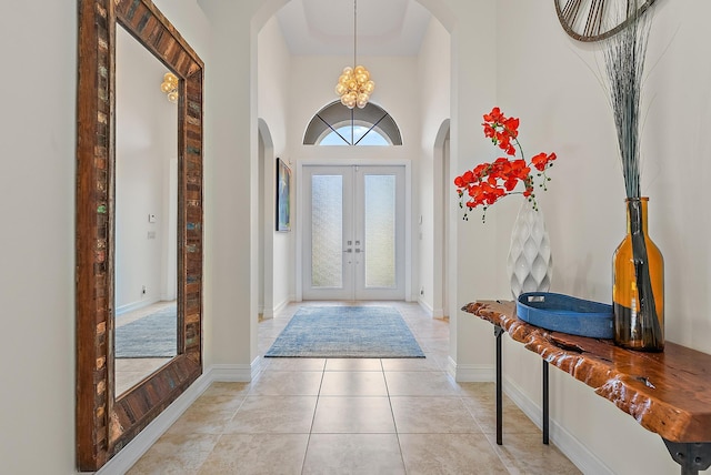 tiled foyer featuring a high ceiling, a chandelier, and french doors