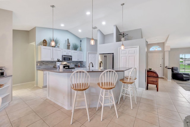 kitchen with appliances with stainless steel finishes, decorative light fixtures, white cabinetry, a center island with sink, and a breakfast bar area