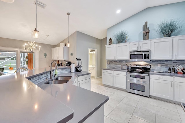 kitchen featuring appliances with stainless steel finishes, decorative light fixtures, white cabinetry, sink, and vaulted ceiling