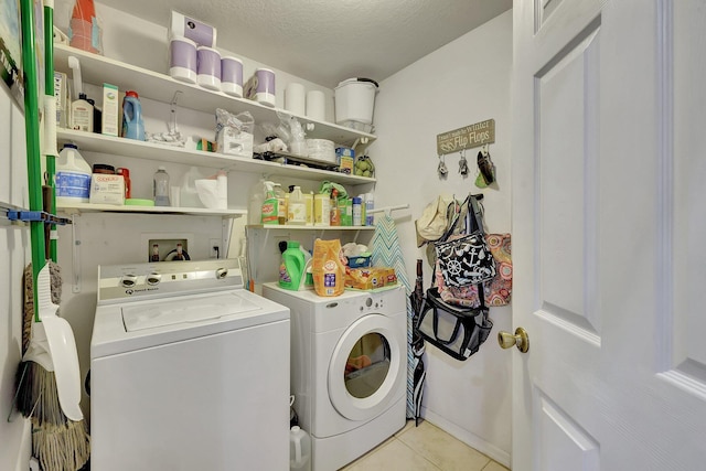 laundry room with a textured ceiling, washing machine and dryer, and light tile patterned floors