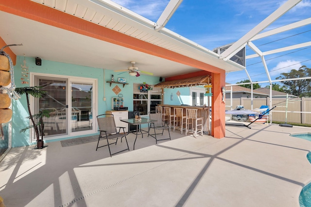 view of patio with ceiling fan, exterior bar, glass enclosure, and a fenced in pool