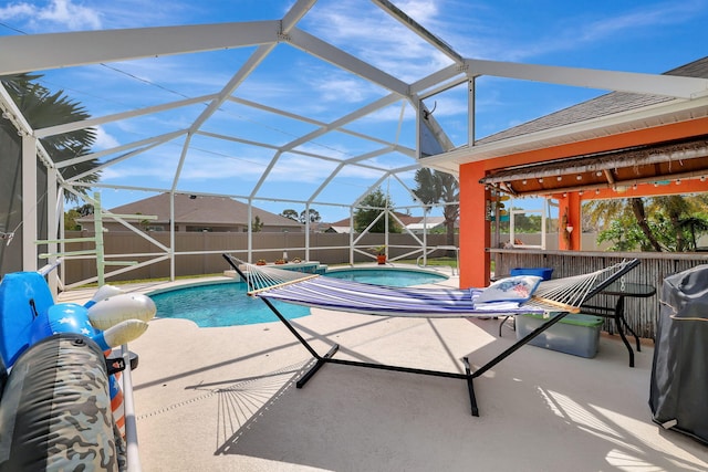 view of pool with glass enclosure, a patio area, and a hot tub