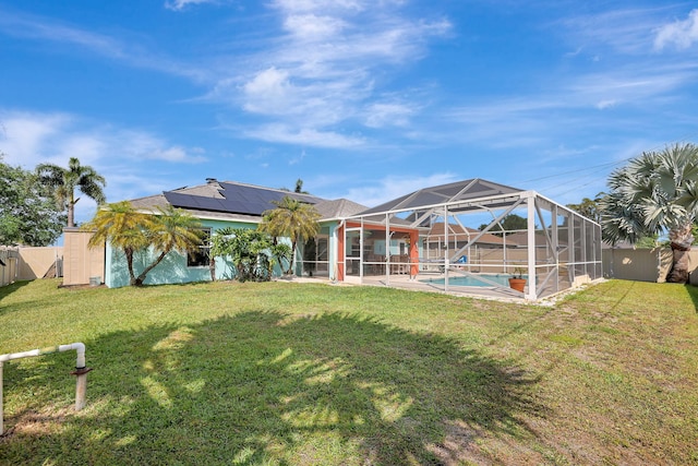 back of house with a fenced in pool, a lanai, a yard, and solar panels