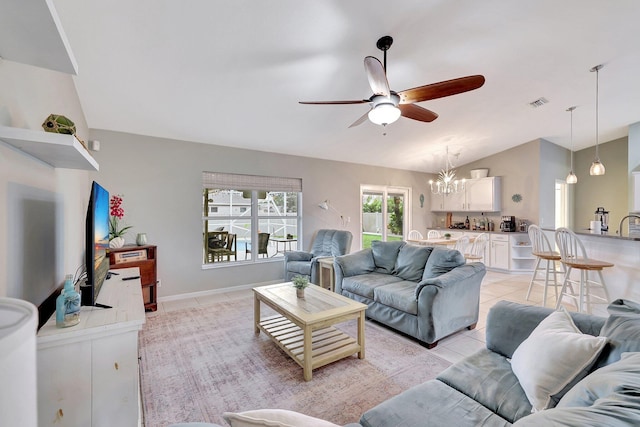 living room featuring ceiling fan with notable chandelier, light tile patterned floors, and lofted ceiling