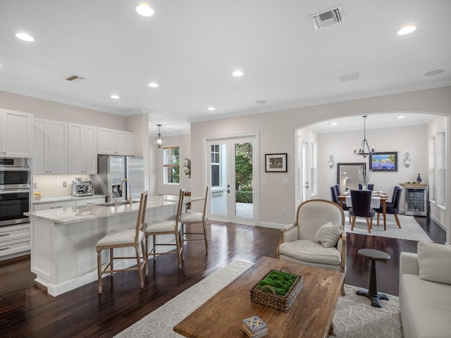 living room with sink, ornamental molding, dark hardwood / wood-style floors, and a chandelier