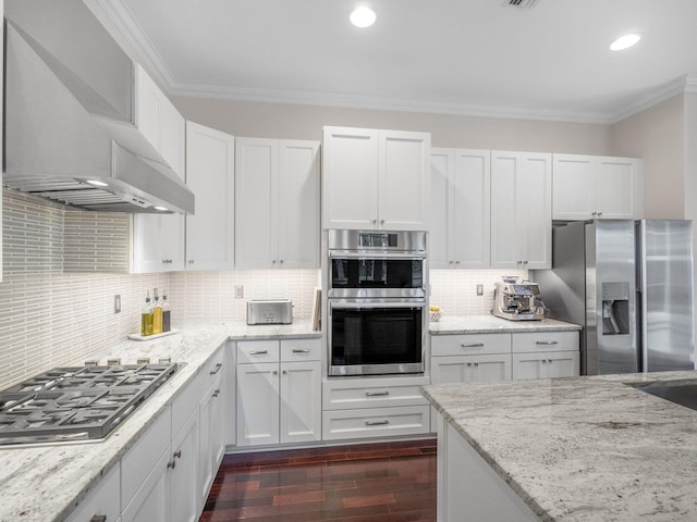 kitchen featuring wall chimney exhaust hood, crown molding, appliances with stainless steel finishes, dark hardwood / wood-style flooring, and white cabinets