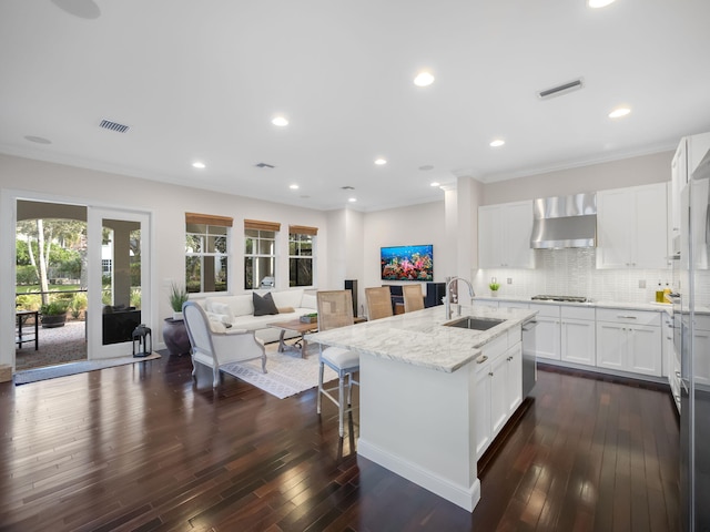 kitchen featuring sink, white cabinets, light stone countertops, a center island with sink, and wall chimney exhaust hood