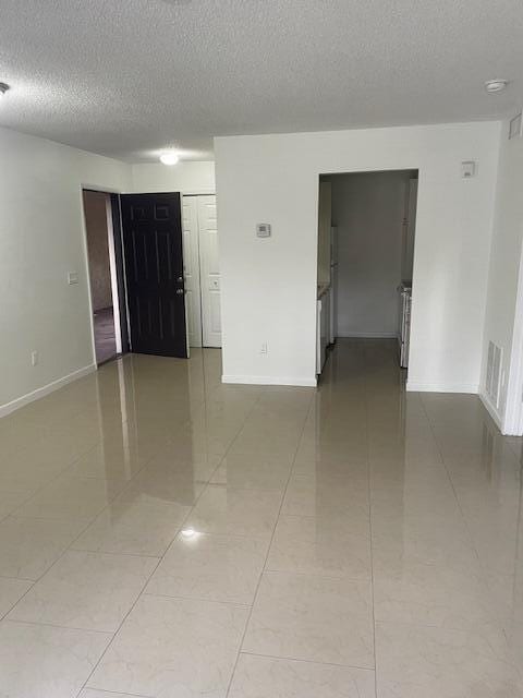 4261 W Mcnab Rd Unit 13, Pompano Beach, FL 33069 - empty room featuring a textured ceiling and light tile patterned floors