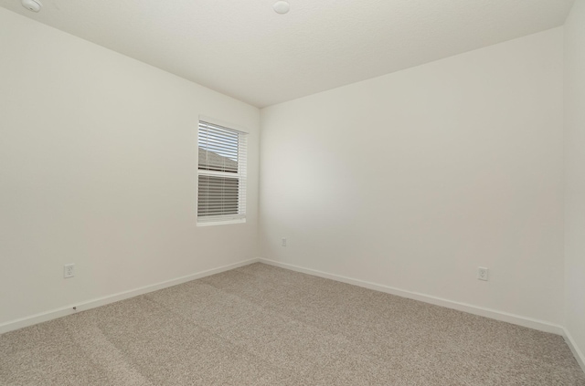 unfurnished room featuring baseboards and light colored carpet