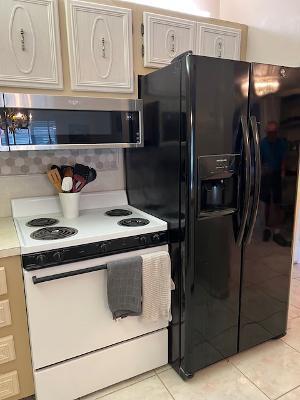 kitchen with white electric stove, light tile patterned floors, and black fridge