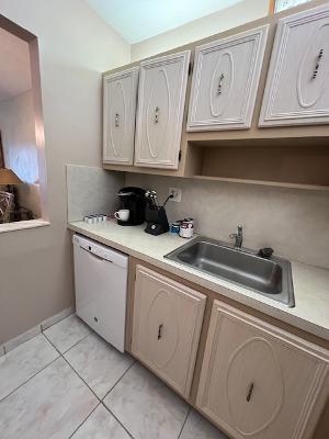 kitchen featuring sink, vaulted ceiling, white dishwasher, and light tile patterned flooring