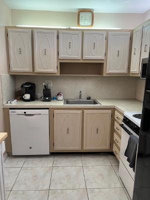 kitchen featuring sink, white appliances, light brown cabinets, and light tile patterned flooring