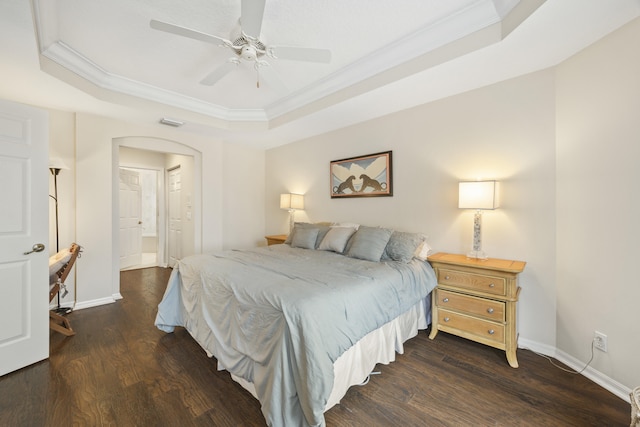 bedroom with ceiling fan, a tray ceiling, dark hardwood / wood-style flooring, and ornamental molding