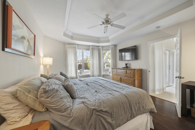 bedroom with ceiling fan, dark hardwood / wood-style flooring, a raised ceiling, a textured ceiling, and ornamental molding