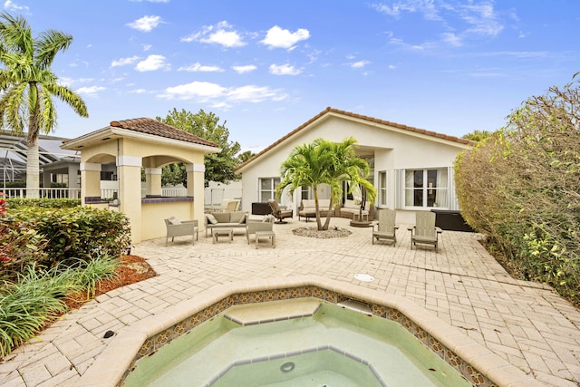 back of property featuring an in ground hot tub, a patio, and outdoor lounge area