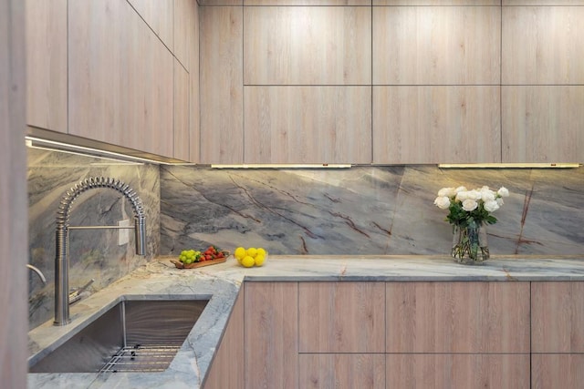 interior details featuring light stone counters, sink, and light brown cabinetry