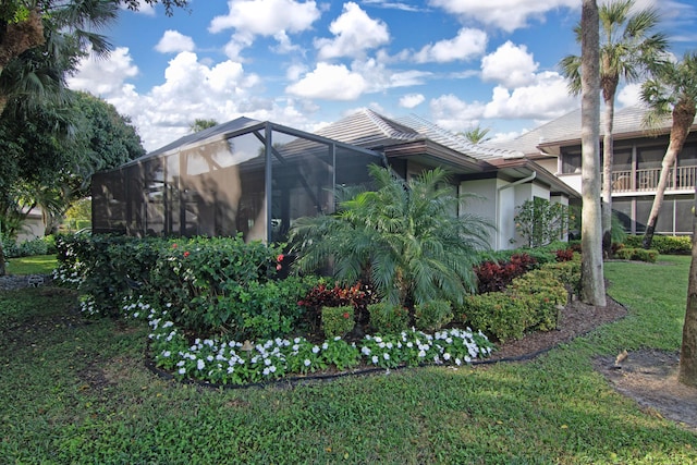 view of side of home with glass enclosure and a yard