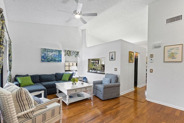 living room featuring ceiling fan, wood-type flooring, high vaulted ceiling, and a textured ceiling