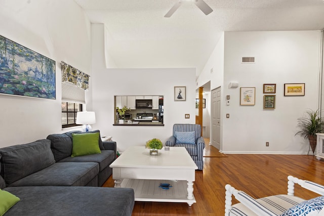 living room with ceiling fan, a towering ceiling, and dark hardwood / wood-style flooring