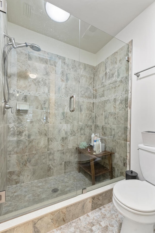 bathroom featuring toilet and an enclosed shower