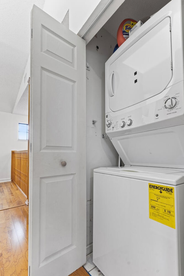 washroom with light hardwood / wood-style flooring and stacked washing maching and dryer