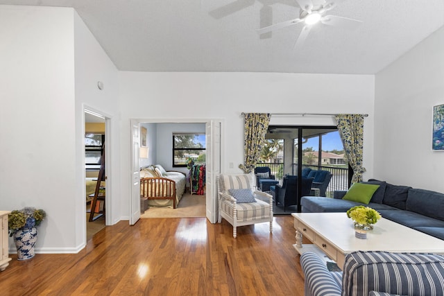 living room featuring dark wood-type flooring, a textured ceiling, and ceiling fan