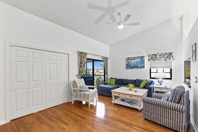 living room with wood-type flooring, a textured ceiling, and high vaulted ceiling