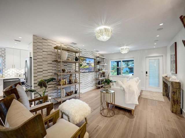 living room featuring a fireplace, light hardwood / wood-style floors, and an inviting chandelier