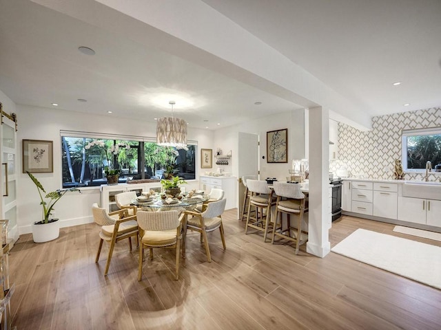 dining space featuring a barn door, sink, a chandelier, and light hardwood / wood-style floors