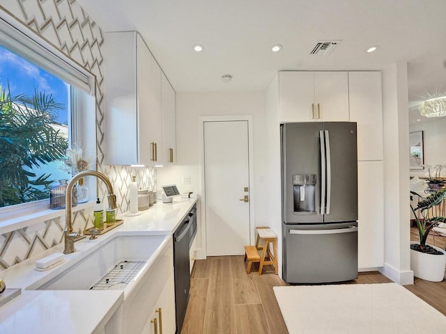 kitchen with light hardwood / wood-style flooring, black dishwasher, white cabinets, and stainless steel fridge