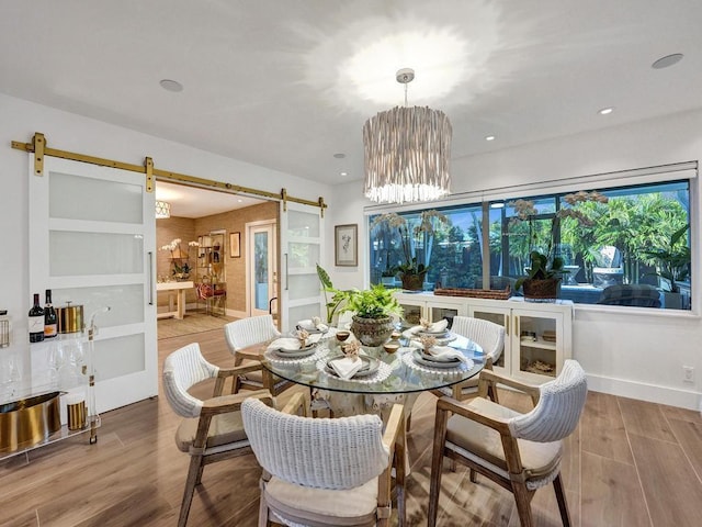 dining space featuring hardwood / wood-style floors, a notable chandelier, and a barn door