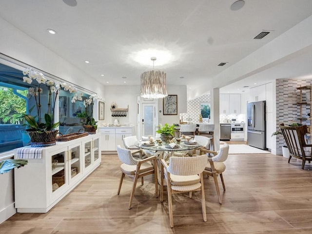 dining space featuring a notable chandelier and light wood-type flooring