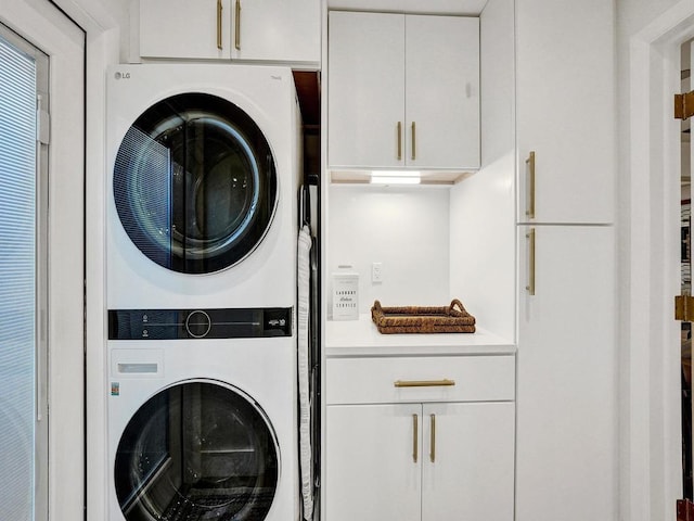 laundry room with stacked washing maching and dryer and cabinets