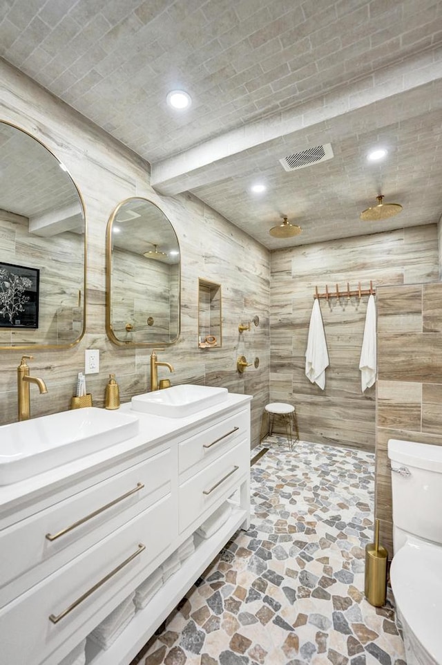 bathroom with toilet, vanity, and beam ceiling