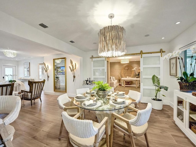 dining space with light hardwood / wood-style floors and a barn door