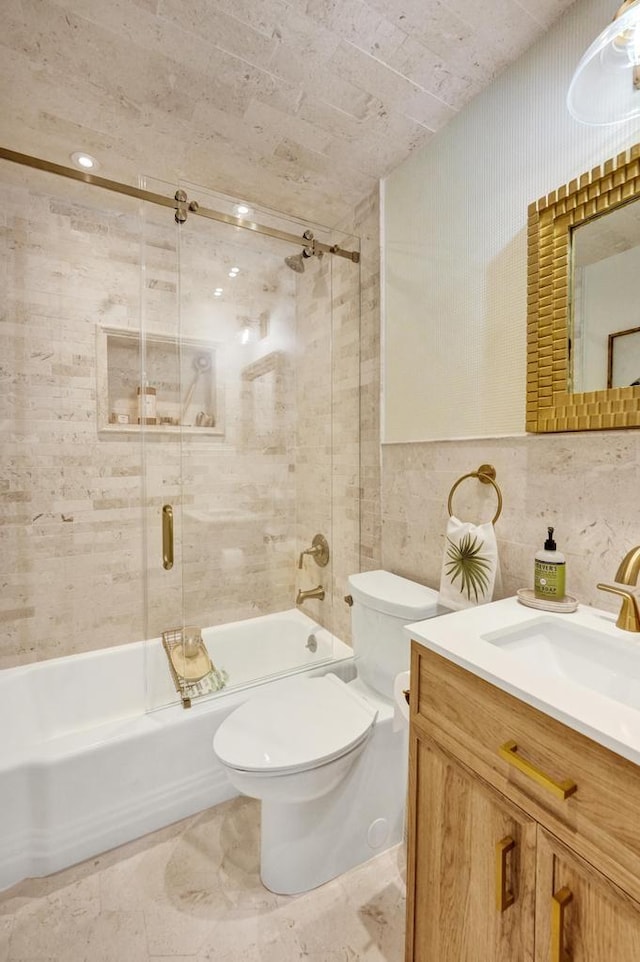 full bathroom with toilet, tile walls, vanity, and tiled shower / bath combo