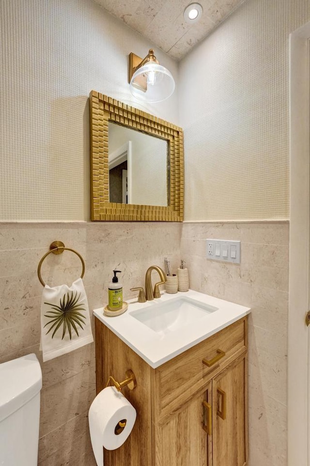 bathroom with toilet, tile walls, and vanity