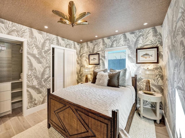 bedroom with a textured ceiling, ceiling fan, a closet, and light hardwood / wood-style floors