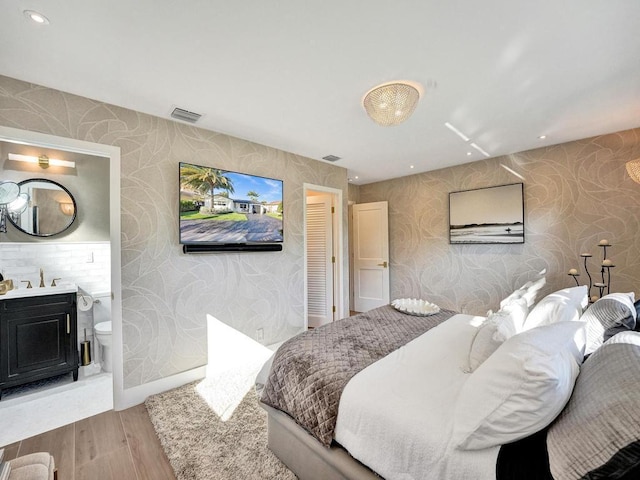 bedroom featuring sink, hardwood / wood-style floors, and ensuite bathroom