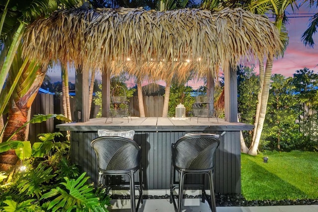 patio terrace at dusk with a yard and an outdoor bar