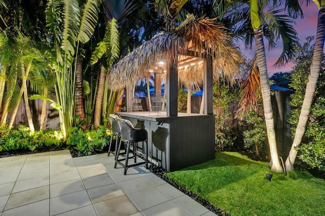 patio terrace at dusk with an outdoor bar and a yard